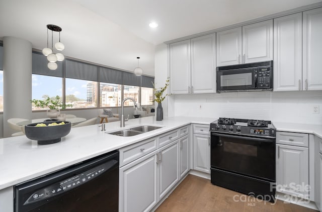 kitchen featuring sink, gray cabinets, kitchen peninsula, pendant lighting, and black appliances