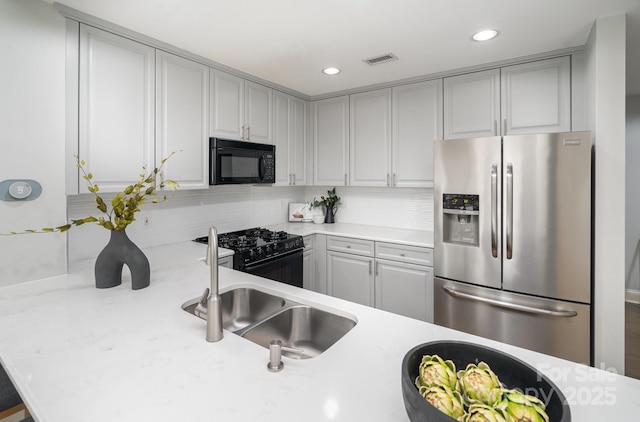 kitchen with gray cabinetry, sink, decorative backsplash, and black appliances