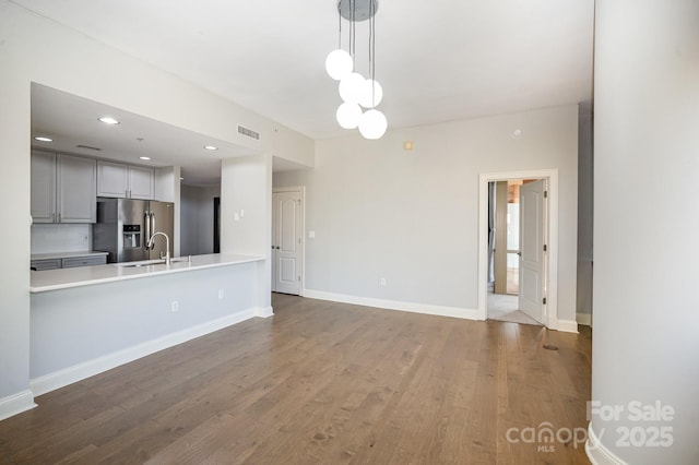 kitchen with sink, gray cabinets, tasteful backsplash, wood-type flooring, and stainless steel fridge with ice dispenser