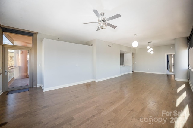 unfurnished living room featuring dark wood-type flooring and ceiling fan