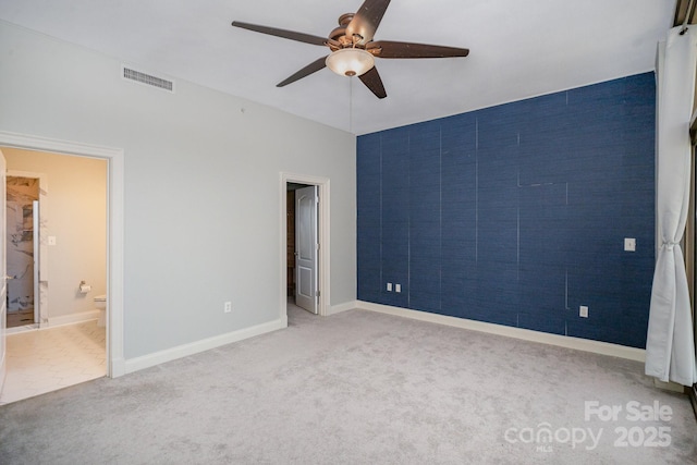 unfurnished bedroom featuring ceiling fan, ensuite bathroom, and light carpet