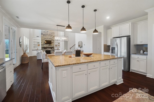 kitchen featuring pendant lighting, white cabinetry, a center island, stainless steel appliances, and light stone countertops