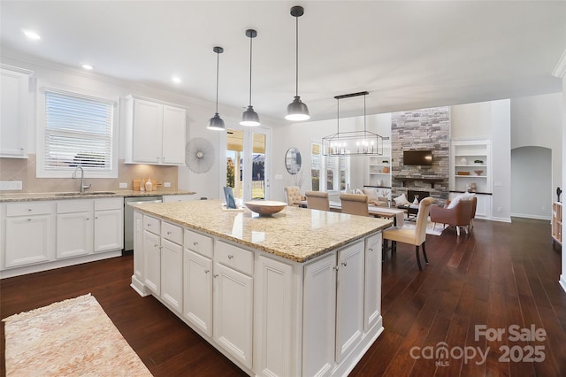 kitchen with sink, stainless steel dishwasher, dark hardwood / wood-style flooring, pendant lighting, and white cabinets