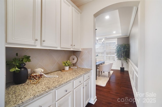 kitchen featuring crown molding, light stone countertops, dark hardwood / wood-style floors, and white cabinets