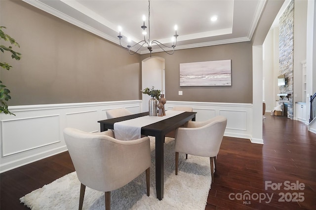 dining space featuring dark hardwood / wood-style floors, a tray ceiling, an inviting chandelier, and crown molding