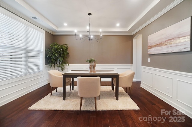 dining area with a raised ceiling, a notable chandelier, and dark hardwood / wood-style flooring