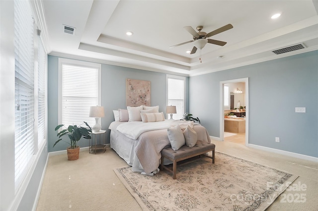 bedroom featuring ensuite bath, ceiling fan, a tray ceiling, ornamental molding, and light colored carpet