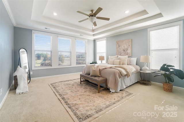 bedroom with ceiling fan, light colored carpet, a tray ceiling, and multiple windows