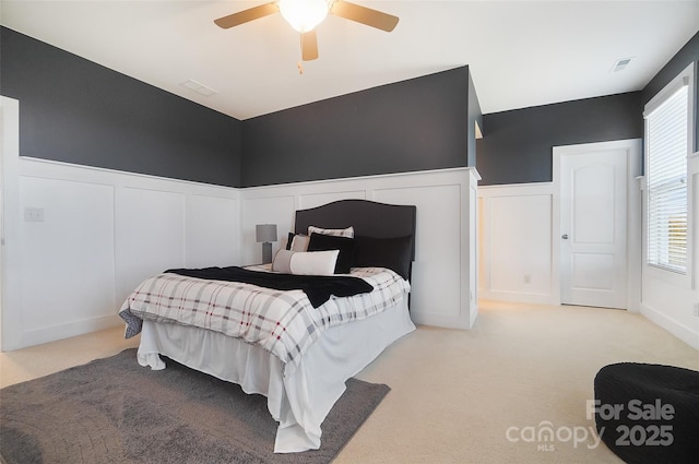 carpeted bedroom featuring multiple windows and ceiling fan