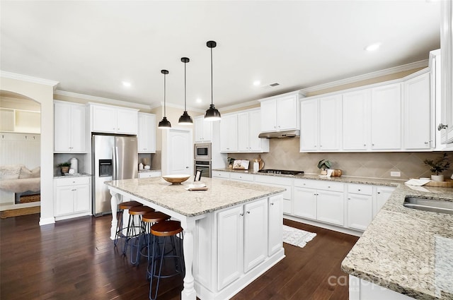 kitchen with white cabinets, hanging light fixtures, ornamental molding, a center island, and stainless steel appliances