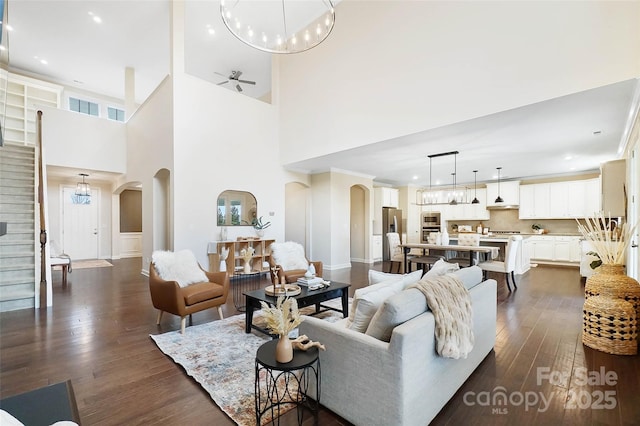 living room featuring ceiling fan with notable chandelier and dark hardwood / wood-style flooring