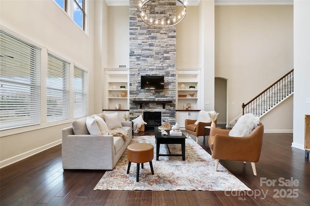 living room with an inviting chandelier, a fireplace, dark hardwood / wood-style floors, and a towering ceiling