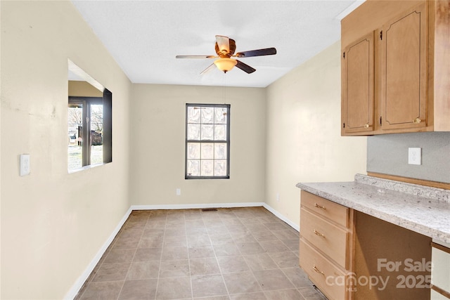 interior space with light stone countertops and ceiling fan