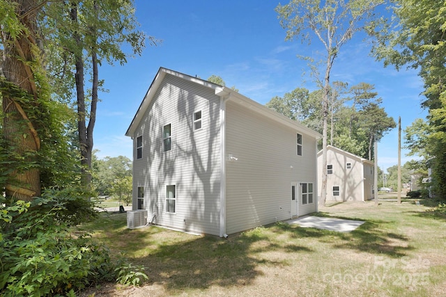 rear view of property with cooling unit and a yard