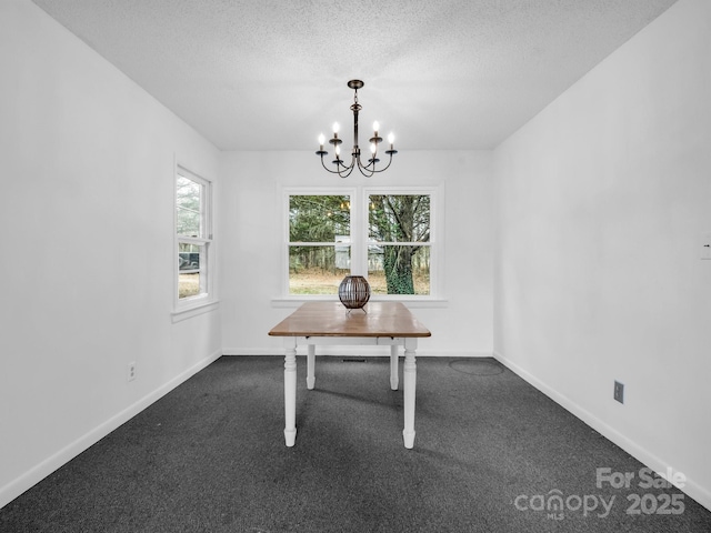 unfurnished dining area with an inviting chandelier, dark carpet, and a textured ceiling