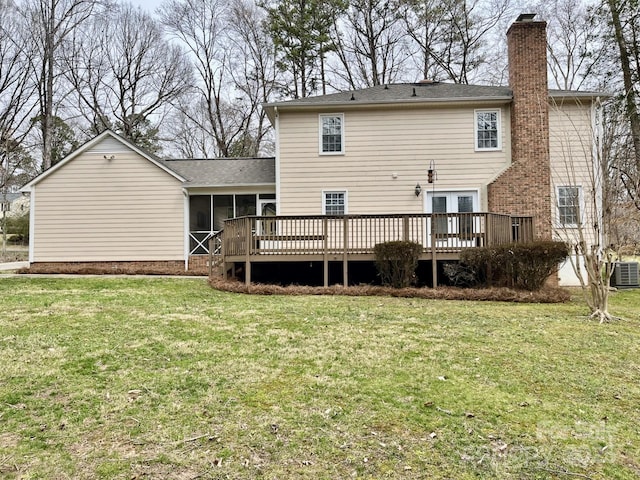 rear view of property with a wooden deck, a lawn, a chimney, and a sunroom