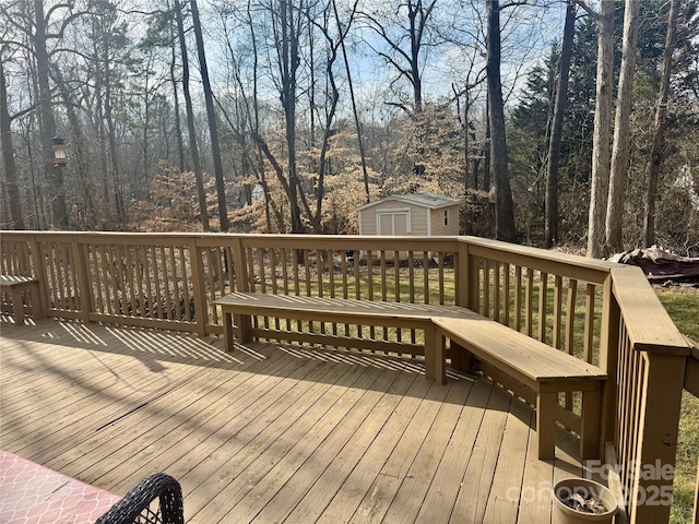 wooden terrace with a storage shed, a view of trees, and an outdoor structure