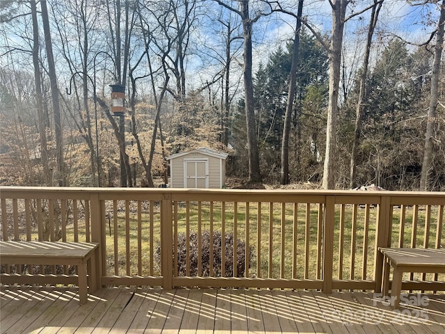 wooden deck featuring an outbuilding, a wooded view, and a shed