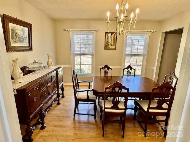 dining area with plenty of natural light, a textured ceiling, an inviting chandelier, and light wood-style flooring