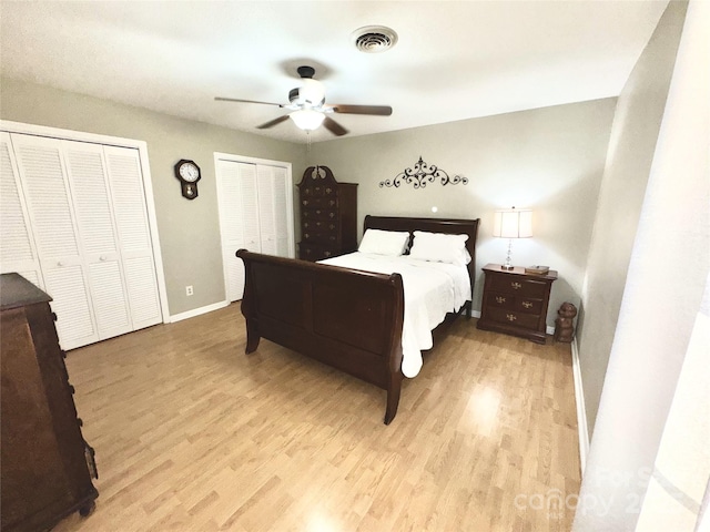 bedroom with light wood-style floors, visible vents, two closets, and baseboards