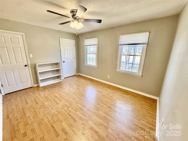 unfurnished bedroom featuring baseboards, a textured ceiling, wood finished floors, and a ceiling fan