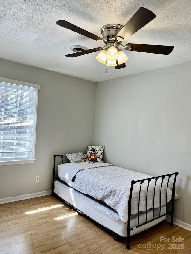 bedroom featuring wood finished floors, baseboards, and ceiling fan