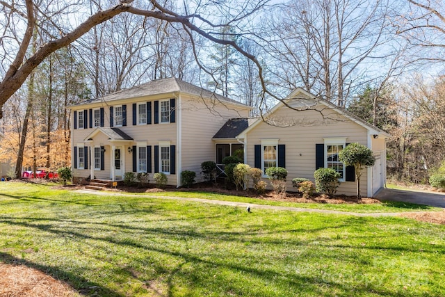 colonial-style house featuring a front lawn, a garage, and driveway