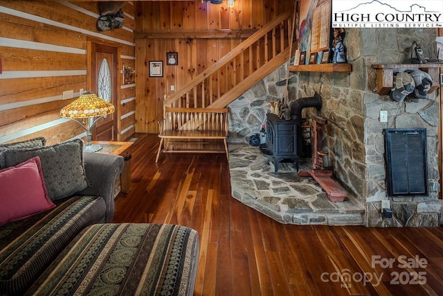 living room featuring dark wood-type flooring, heating unit, a wood stove, and wood walls