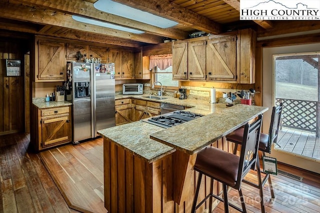 kitchen featuring beamed ceiling, sink, kitchen peninsula, stainless steel appliances, and light wood-type flooring