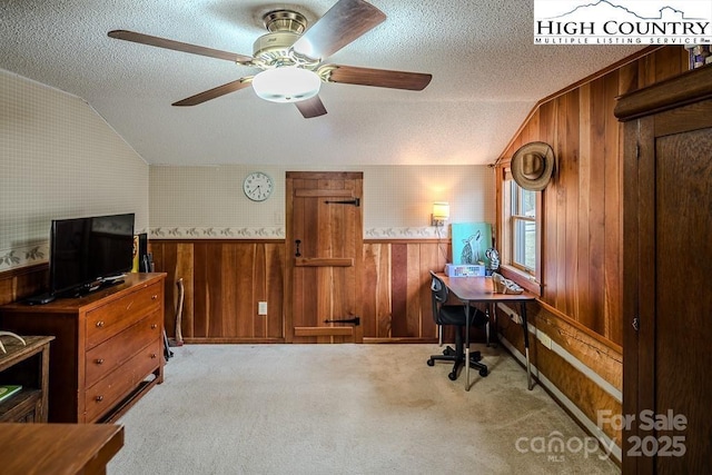 office featuring light carpet, vaulted ceiling, a textured ceiling, and wood walls