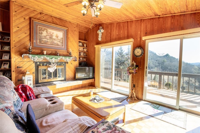 living room featuring built in shelves, wood walls, wood ceiling, vaulted ceiling, and ceiling fan