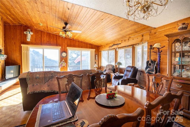 dining room featuring vaulted ceiling, plenty of natural light, and wood walls