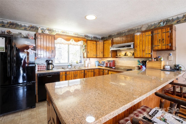 kitchen with sink, kitchen peninsula, a kitchen bar, and black appliances