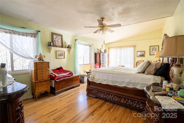 bedroom featuring lofted ceiling, a textured ceiling, and light wood-type flooring