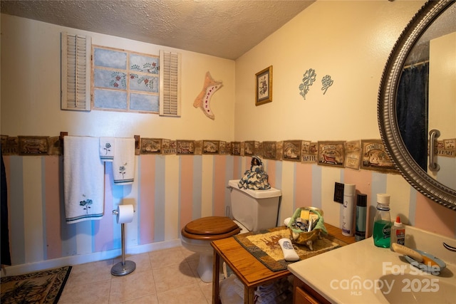 bathroom featuring vanity, toilet, tile patterned flooring, and a textured ceiling