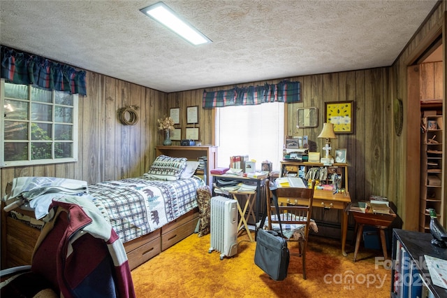 carpeted bedroom featuring a textured ceiling and wood walls