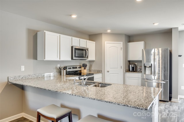 kitchen featuring appliances with stainless steel finishes, kitchen peninsula, light stone countertops, and white cabinets