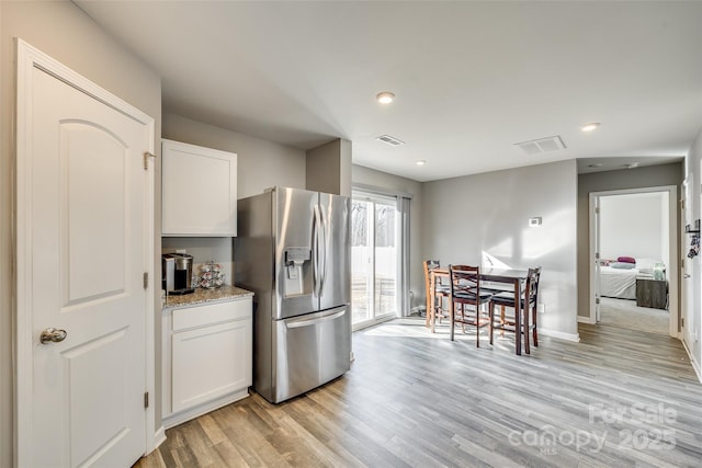 kitchen featuring stainless steel refrigerator with ice dispenser, white cabinets, and light wood-type flooring