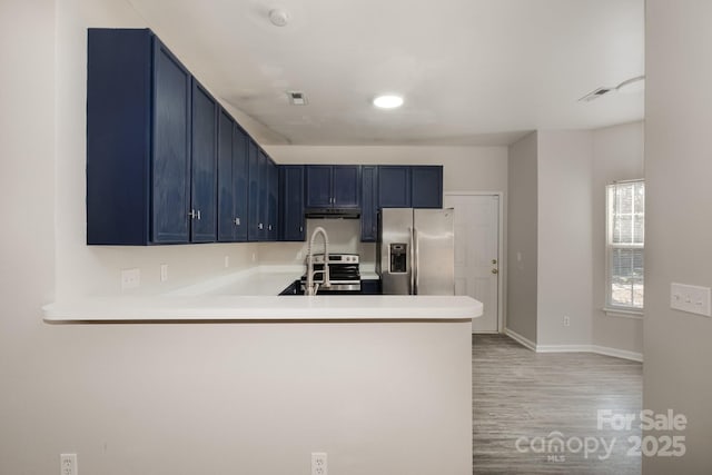 kitchen featuring sink, blue cabinetry, stainless steel appliances, kitchen peninsula, and light wood-type flooring