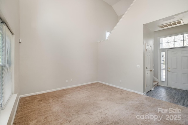 foyer with carpet flooring and high vaulted ceiling