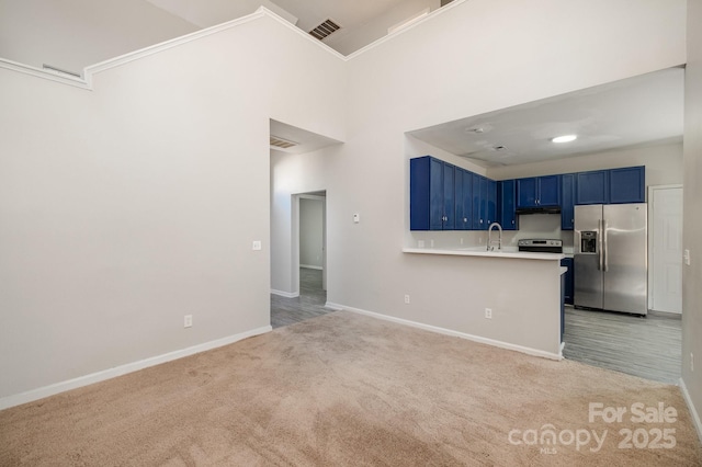 kitchen featuring blue cabinets, sink, kitchen peninsula, light colored carpet, and stainless steel appliances