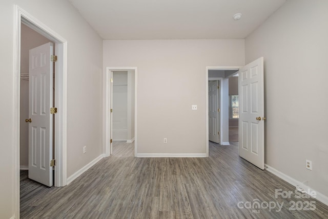 unfurnished bedroom with a walk in closet, hardwood / wood-style floors, and a closet