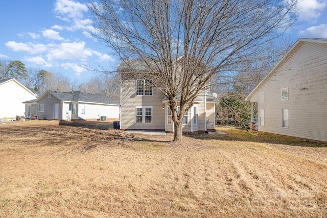 back of property with a yard and central AC