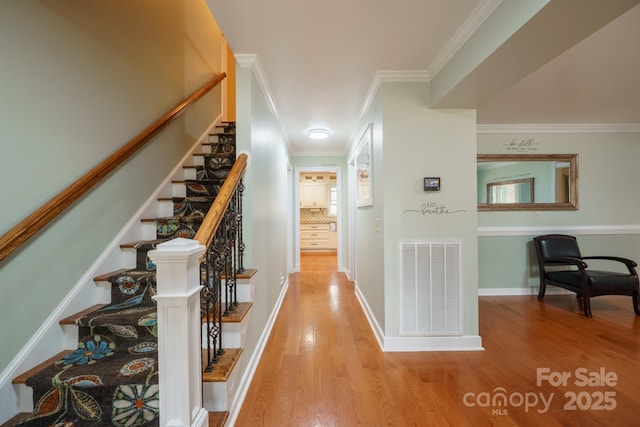 hall with ornamental molding and light wood-type flooring