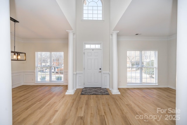 entryway featuring crown molding, light hardwood / wood-style flooring, and ornate columns