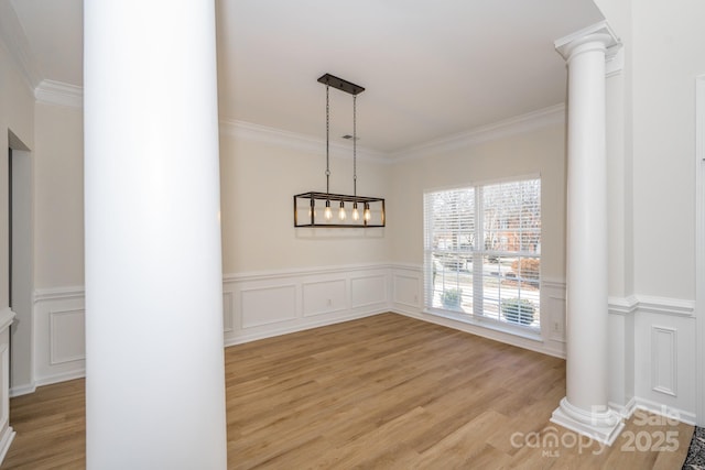 unfurnished dining area featuring ornamental molding, decorative columns, and light hardwood / wood-style floors