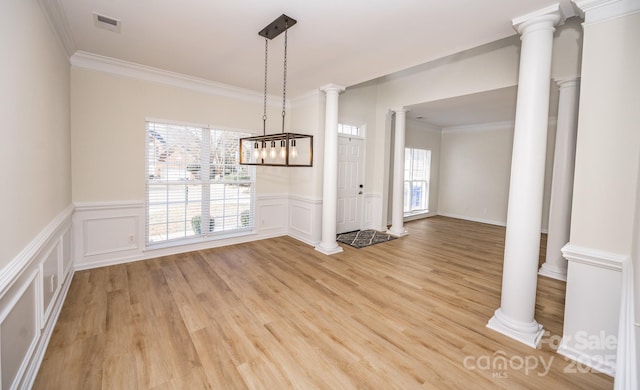 unfurnished dining area featuring ornamental molding, decorative columns, and light hardwood / wood-style flooring