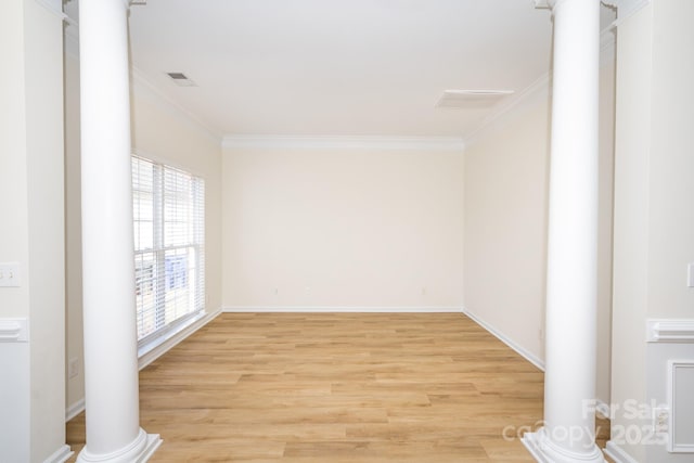 spare room featuring ornamental molding, decorative columns, and light wood-type flooring