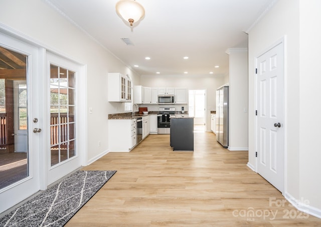 kitchen with white cabinetry, crown molding, a center island, stainless steel appliances, and light hardwood / wood-style floors