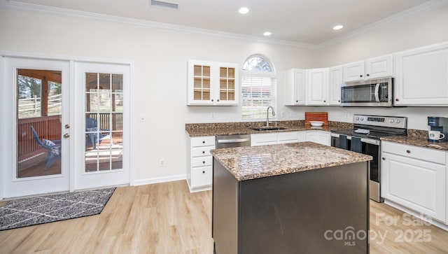 kitchen with sink, white cabinetry, dark stone counters, a kitchen island, and stainless steel appliances